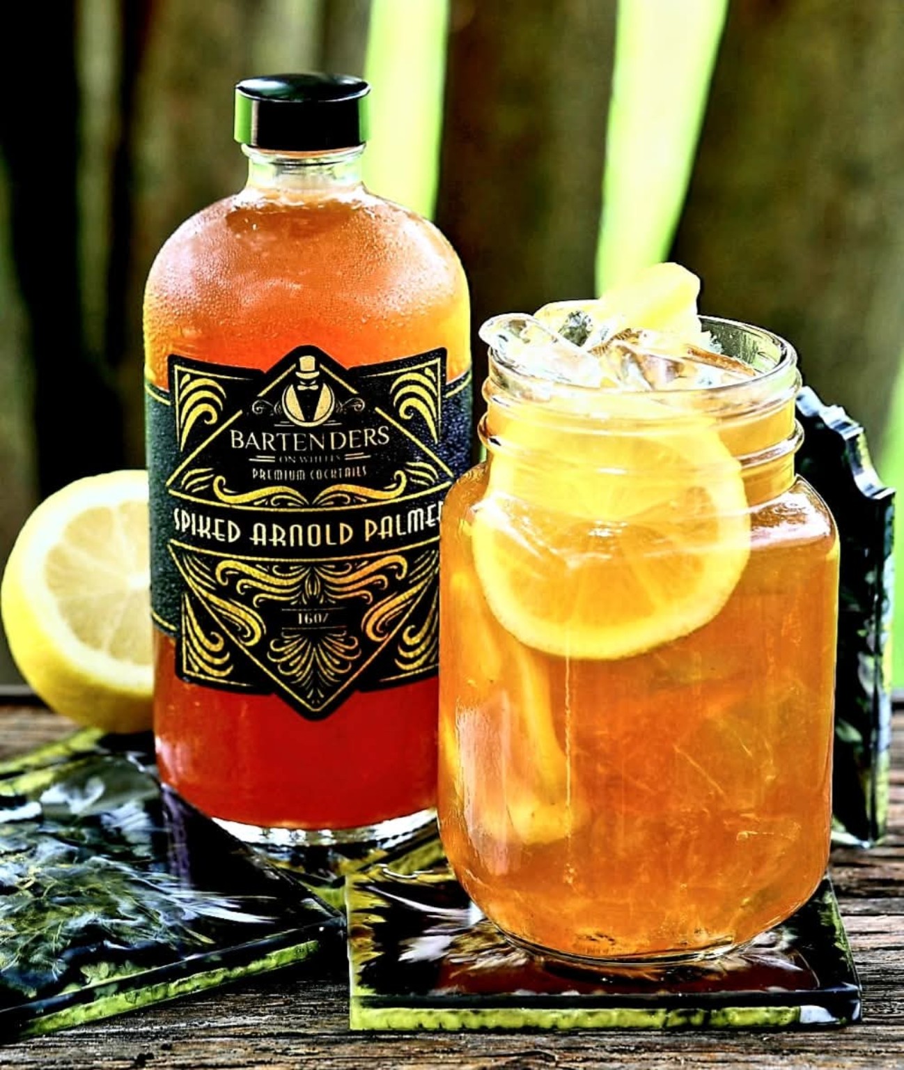 Bartenders On Wheels Spiked Arnold Palmer bottle beside an iced cocktail with lemon.